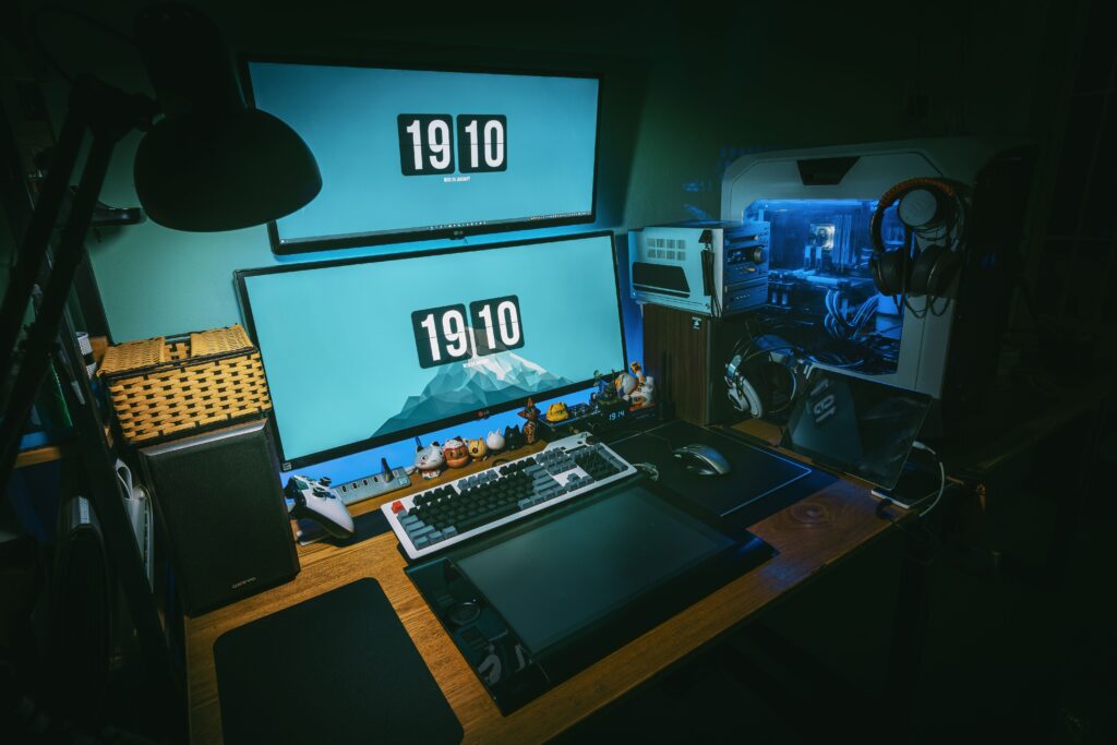 Equipo de gaming con dos monitores en una habitación con poca luz; imagen ilustrativa.